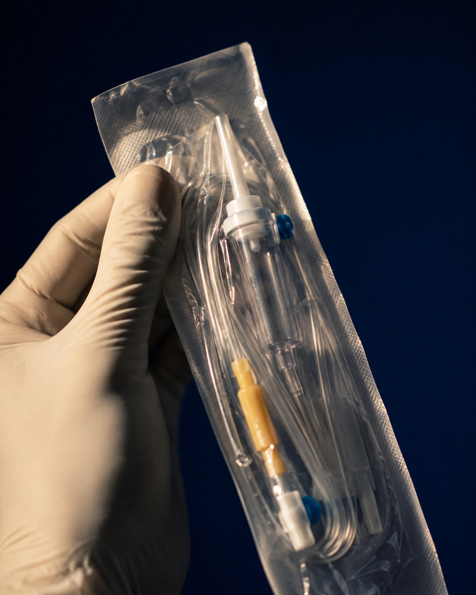 Gloved hand holding a sealed IV drip line, ready for a mobile visit in Los Cabos